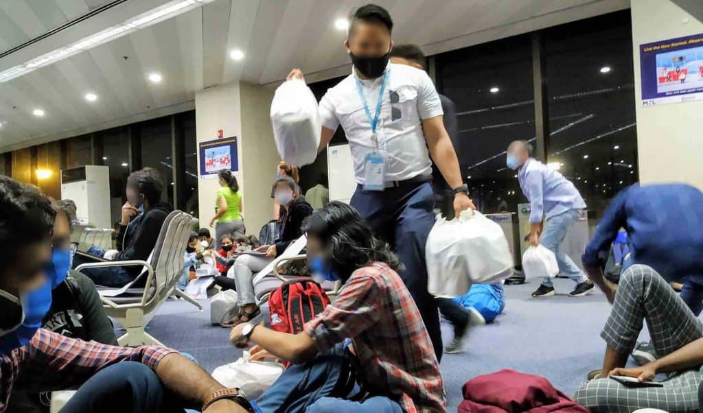 Indian Embassy staff distributing food to repatriation flight passengers in the lounge